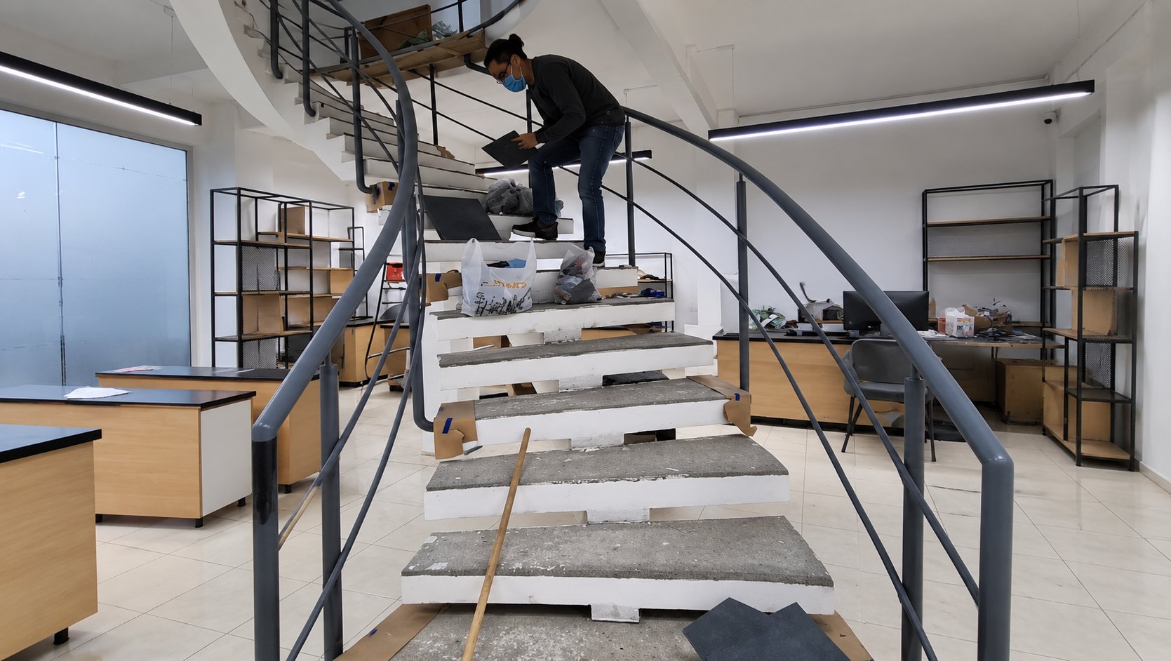 Renovación de la escalera: escalones en obra cubiertos con cartón y un instalador tomando medidas
