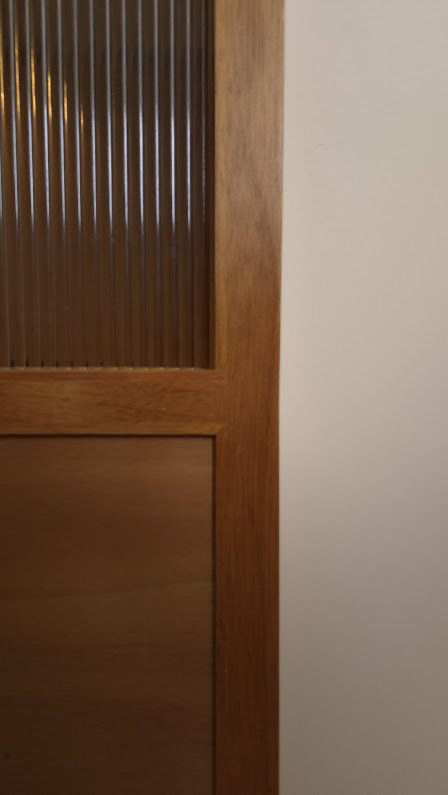 Detalle de una puerta de madera con vidrio acanalado